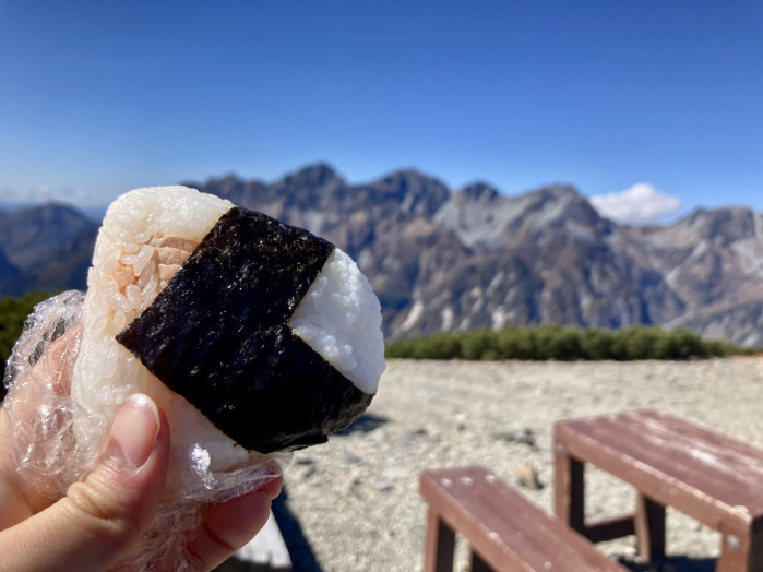 最高のランチスポットでお昼ごはん！しかし、0℃近い気温に冷たい風が吹き荒れて、ピクニックどころではありませんでした・・・。一口おにぎりをかじったら耐え切れずに蝶ヶ岳ヒュッテへ避難。